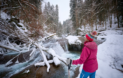 nice and active senior woman hiking in snowy and ice covered Eistobel Canyon in the Allgau alps near Gruenenbach, Bavaria, Germany