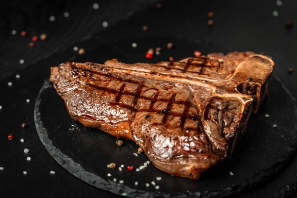 Dry Aged Barbecue Porterhouse Steak T-bone beef steak sliced with large fillet piece with herbs and salt. American meat restaurant stock photo