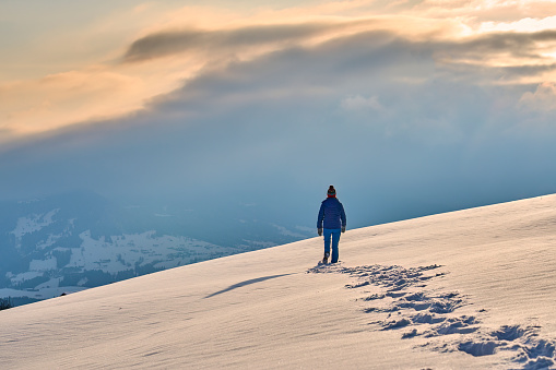 nice and active senior woman snowshoeing in deep powder snow during sunset in the mountains of the Allgau Alps near Oberstaufen, Bavaria, Austria
