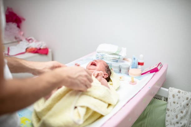 Mother cleaning a baby after bath with a towel.