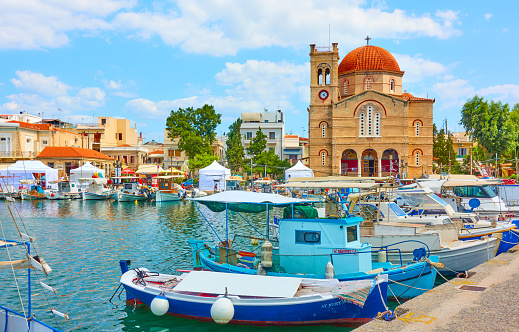 Aegina, Greece - September 13, 2019: View of Aegina town with Ekklisia Isodia Theotokou Church and moored fshing boats