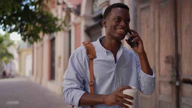 Young man having a phone call and walking outdoors