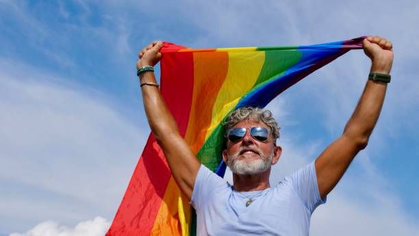 istock Gay gray-haired holds LGBT flag against a sky 1463470064