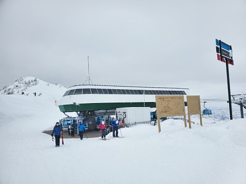 Snowbasin, Utah, USA- January 25, 2023: Skiers disembarking the Strawberry Express Gondola at the top of Snowbasin ski resort in Utah on a foggy flat light day.