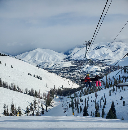 Sun Valley, Idaho, USA- January 27, 2023: Skiers on Frenchman's lift with Sun Valley and Ketchum in the valley far below. Sun Valley Ski Resort, Idaho.