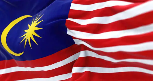 Detail of the Malaysia national flag waving in the wind. Malaysia is a federal state in Southeast Asia. Rippled fabric. Textured background. Realistic 3d illustration. Close-up. Selective focus