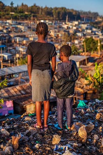 African little girls standing in trash and looking at houses in Kibera slum, Kenya, East Africa. Kibera is the largest slum in Nairobi, the largest urban slum in Africa, and the third largest in the world