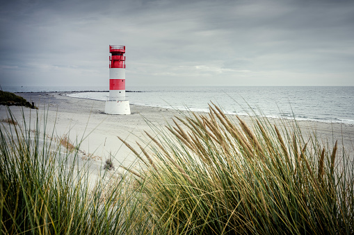 high lighthouse on a sandy shore full of dunes