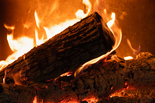 A glimpse at wood logs and embers burning in a high efficiency fireplace which helps heating the house during  a very cold winter day, with a temperature at minus 40 degrees Celsius.
