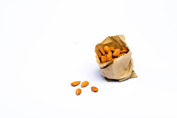 View of fresh almonds in brown paper bag over white background