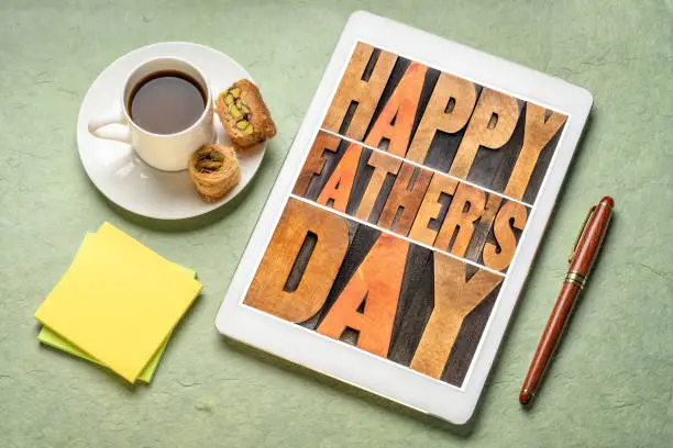 happy father's day - a word abstract in vintage letterpress wood type on a digital tablet with a cup of coffee, greeting card