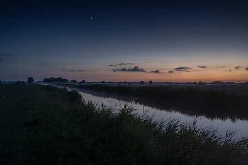The Ems-Jade-Kanal between agricultural fields at dusk in summer. Sande, Friesland, Lower Saxony, Germany