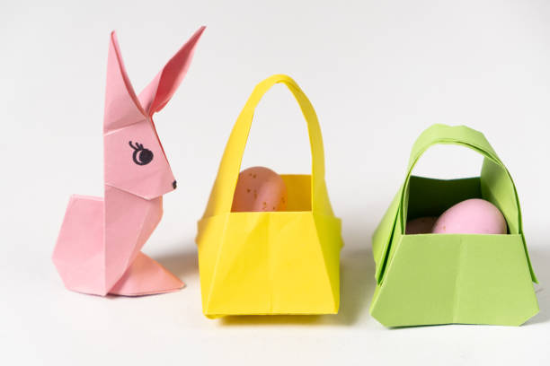 una figurina di coniglietto pasquale fatta di carta, origami e cestini con uova su sfondo bianco - easter egg figurine easter holiday foto e immagini stock