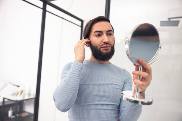 istock Focused transgender person examining his appearance after the makeup application 1463483811