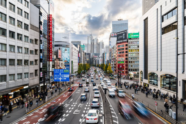 道路交差点での自動車交通輸送の動きのぼかし、日本人は東京都新宿区の交差点を歩き、オフィスビルの街並み。アジアの交通、アジアの都市生活のコンセプト - car driving transportation tokyo prefecture ストックフォトと画像