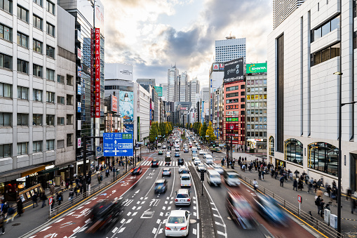Motion blur of car traffic transportation on road intersection, Japanese people walk cross junction in Shinjuku district Tokyo Japan, office building cityscape. Asia transport, Asian city life concept