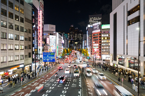 Night motion blur of car traffic transportation on road intersection, Japanese people walk cross junction in Shinjuku Tokyo Japan, office building cityscape. Asia transport, Asian city life concept