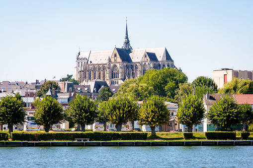 Saint-Quentin, France - August 9, 2022: Southern facade of the basilica of Saint-Quentin seen from the Etand d'Isle beach on a sunny summer day.