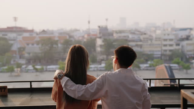 Young couple on the rooftop watching the sun set over the city