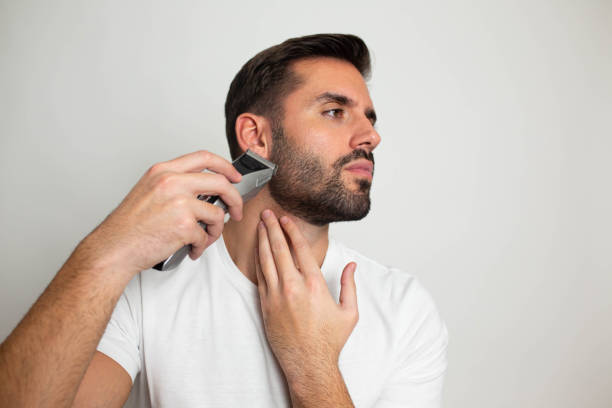 istock Handsome bearded man trimming his beard with a trimmer 1463485238