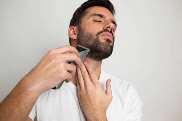 istock Handsome bearded man trimming his beard with a trimmer 1463485350