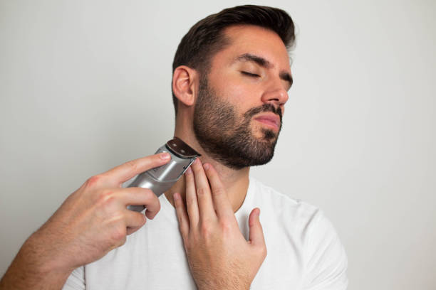 istock Handsome bearded man trimming his beard with a trimmer 1463485360
