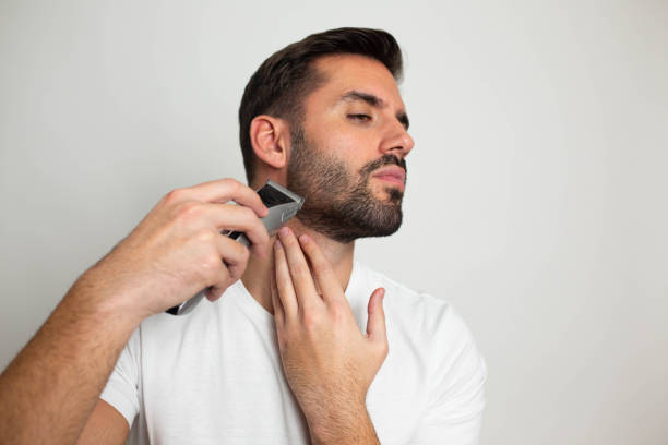 istock Handsome bearded man trimming his beard with a trimmer 1463485416