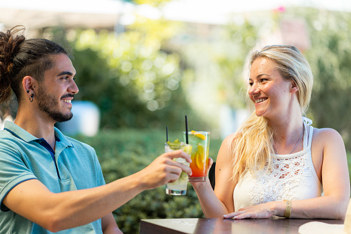 Happy man and woman toasting whit cocktails at bar during summer day