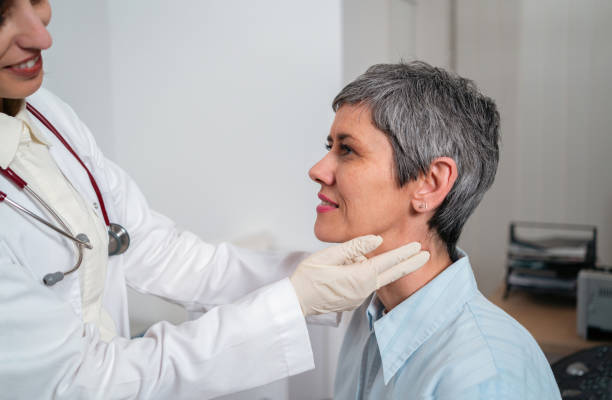Female doctor palpating female patient thyroid gland stock photo