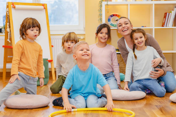 istock Teacher with children in a Kindergarten Classroom. Healthy learning environment. Kindergarten teacher, building relationships with the kids. Cheerful preschool children 1463489084