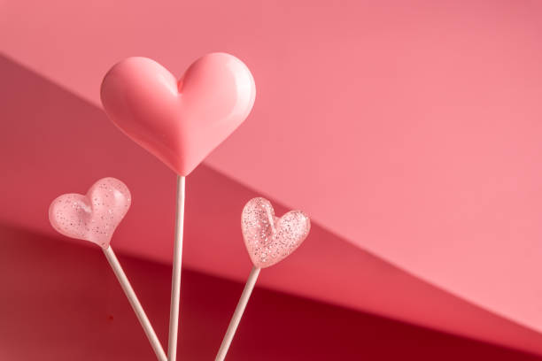 istock three Pink Valentine's day heart shape lollipop candy on empty pastel paper background. Love Concept 1463489372