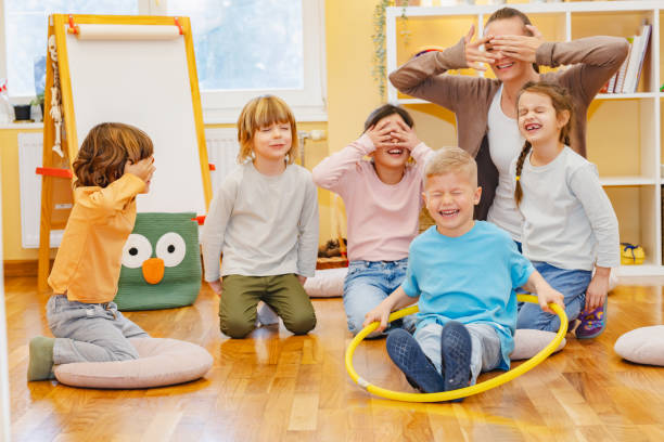 Teacher with children in a Kindergarten Classroom. Healthy learning environment. Kindergarten teacher, building relationships with the kids. Cheerful preschool children