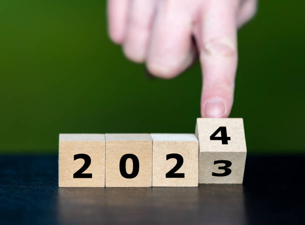 Hand turns cube and changes the year 2023 to year 2024. stock photo