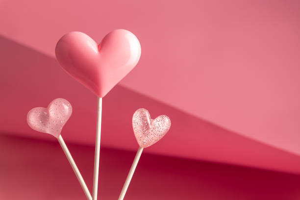 istock three Pink Valentine's day heart shape lollipop candy on empty pastel paper background. Love Concept 1463491111