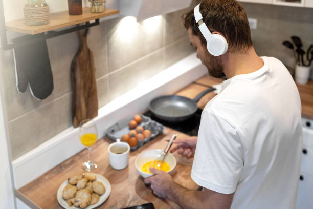 istock Man cooking omelet for breakfast and listening music. 1463492367