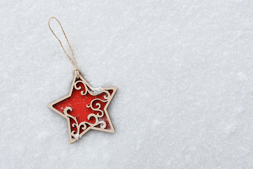 Red wooden star Christmas tree with ornament lies on the snow