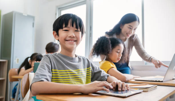 istock Pupil boy, teacher learn computer in classroom at elementary school. Student boy studying primary school. Children coding online in classroom. Education knowledge, successful teamwork concept banner 1463494282