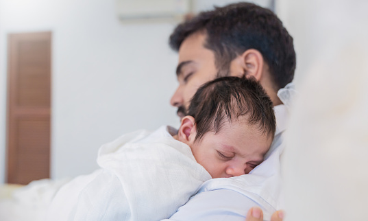 Closeup portrait of young asian Indian father holding his newborn baby with copy space. Healthcare and medical daycare nursery love lifestyle together single dad father day holiday concept
