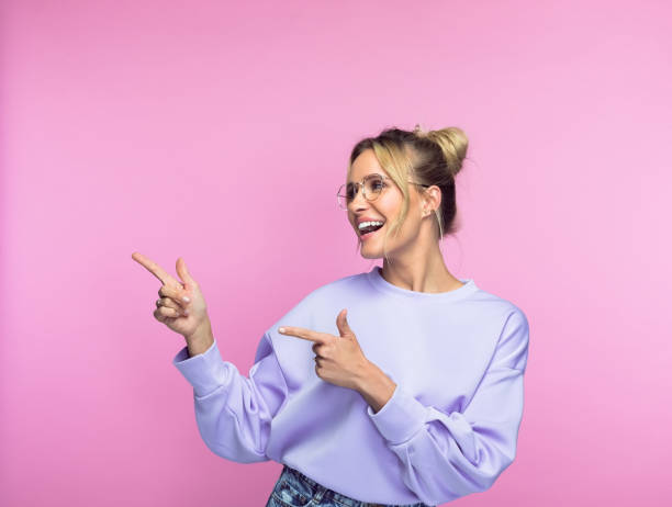 istock Cheerful woman pointing against pink background 1463497768