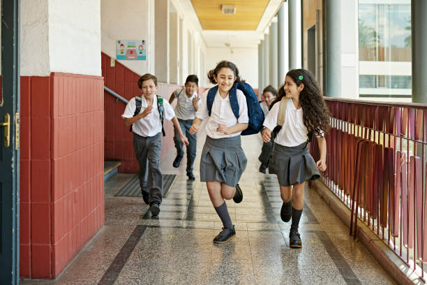 Smiling classmates racing in school hallway stock photo