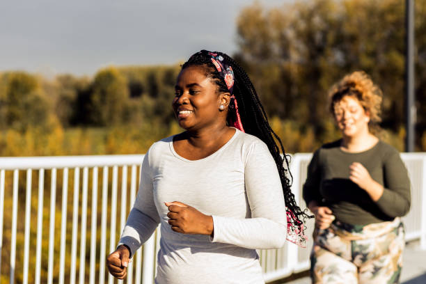 Two young plus size women jogging together. Two young plus size women jogging together. body positive couple stock pictures, royalty-free photos & images