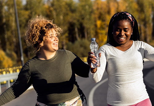 Two excited young plus size women jogging together.