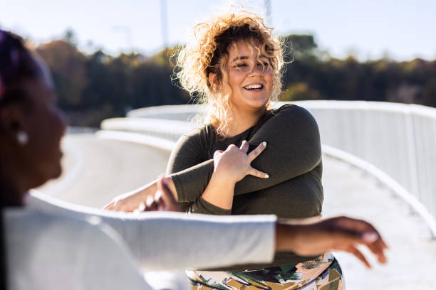 Two young plus size women stretching together before runnung. stock photo