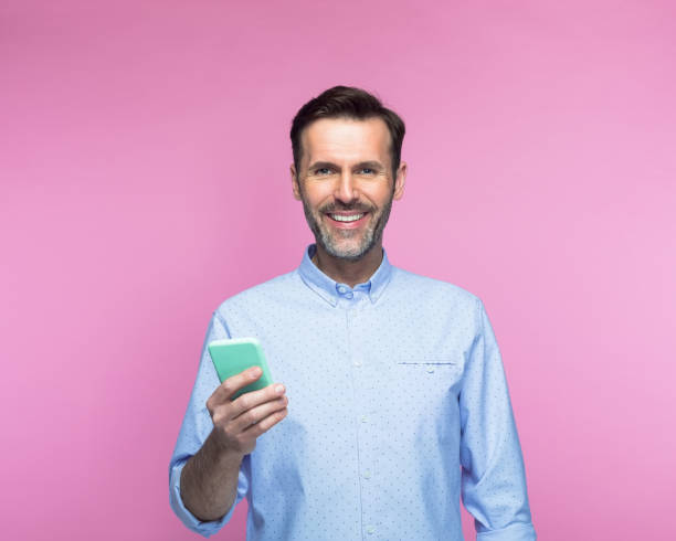 istock Smiling man holding mobile phone 1463501644