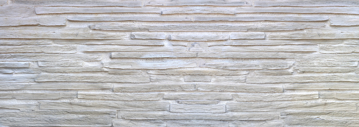 Structure of a bright wall cladding made of long, coarse facing stones with large joints