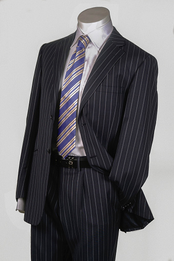 Mannequin wearing a business suit and tie on white background.