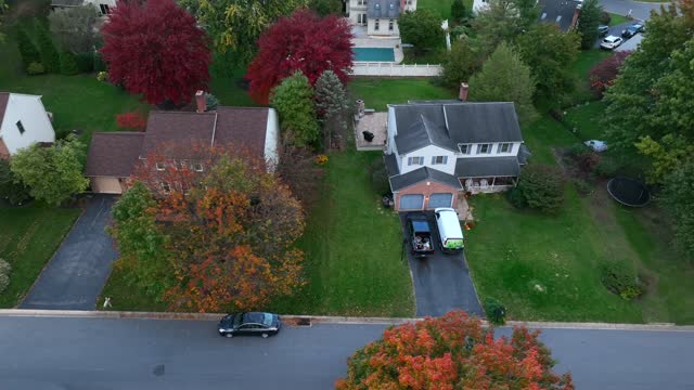 Houses in USA neighborhood. Autumn trees in evening light. Aerial truck shot.