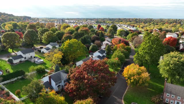 American housing in autumn. Colorful leaves on trees. Golden hour aerial.