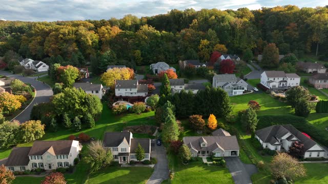 American suburbs in autumn. Colorful fall foliage on mountain with modern USA homes. Aerial truck shot.