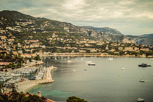 Expensive Condominiums perch on the hillsides above the Mediterranean Sea while sailboats dot the harbour.